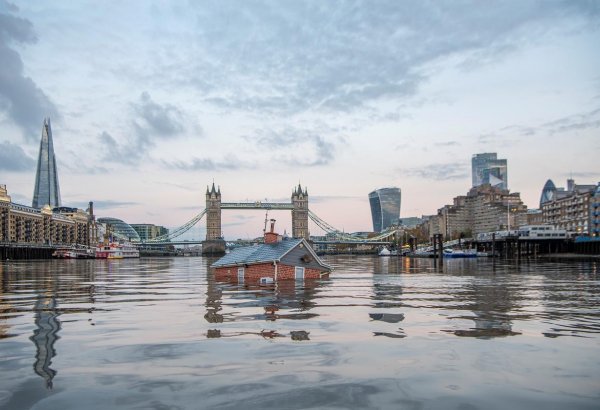 Sinking suburban 'home' drifts down Thames in watery climate protest